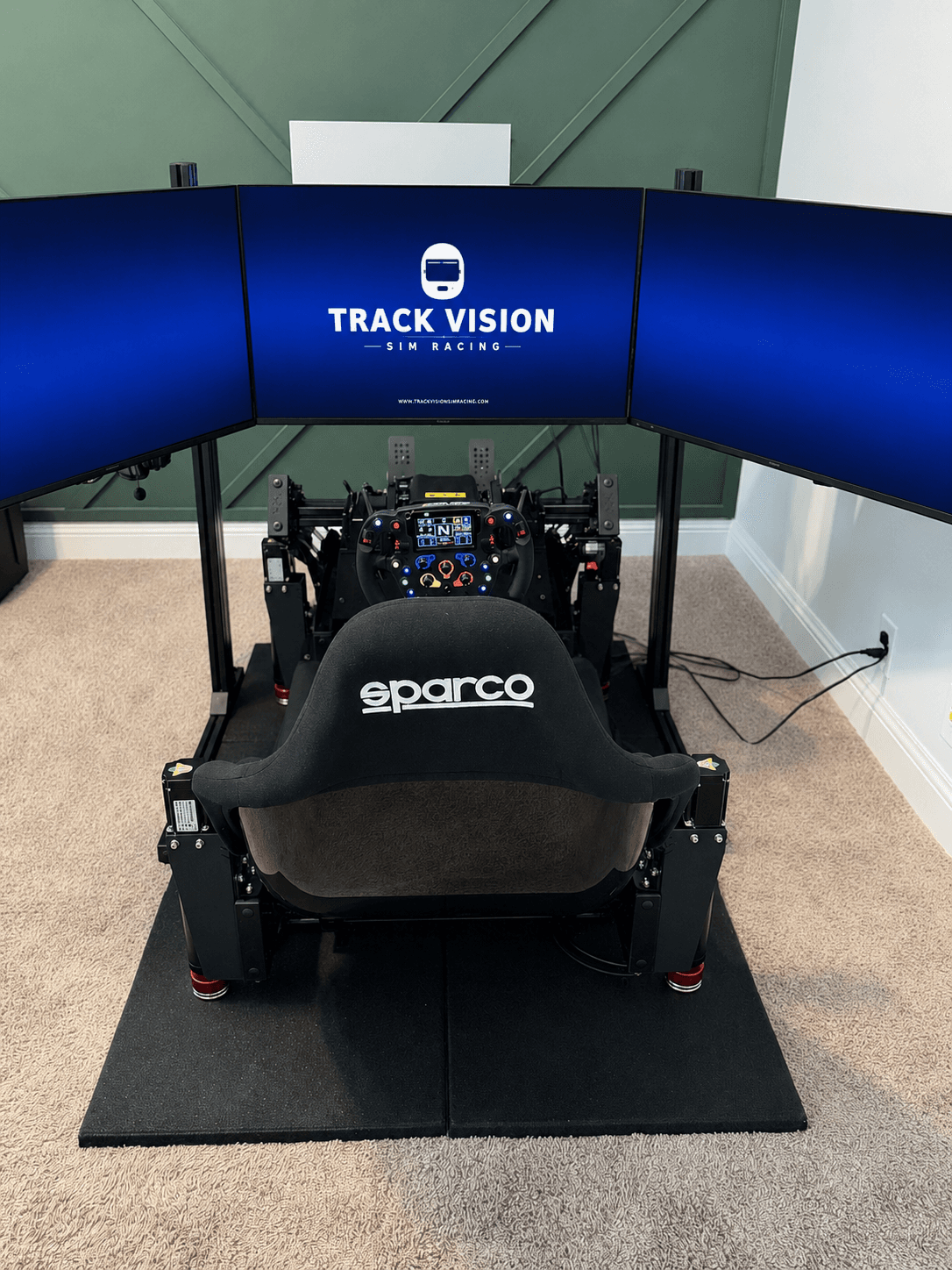 A Track Vision triple-monitor sim racing build with a formula wheel and Sparco seat