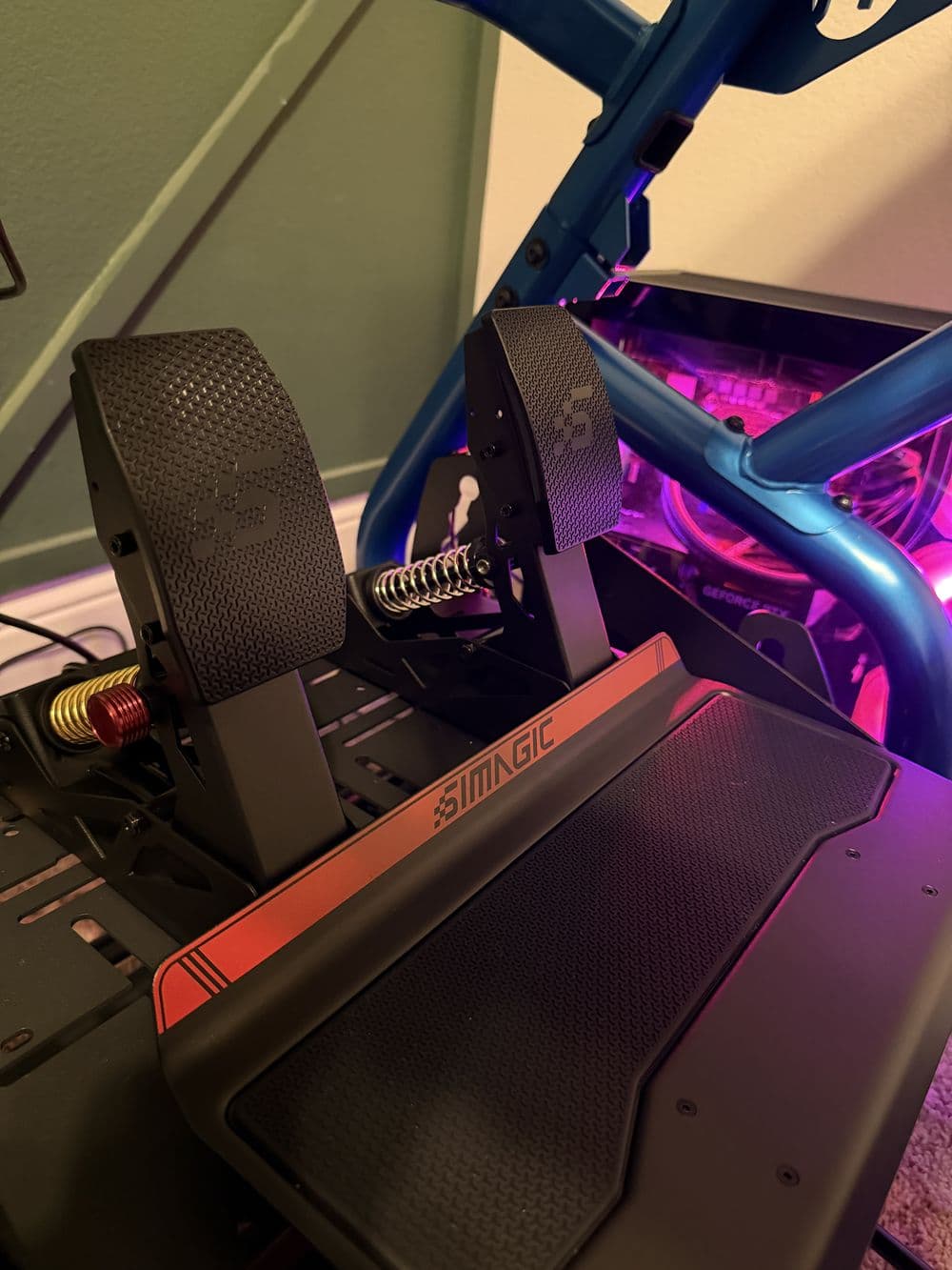 Seat and pedals on the blue tubular rig with a lit PC beside it