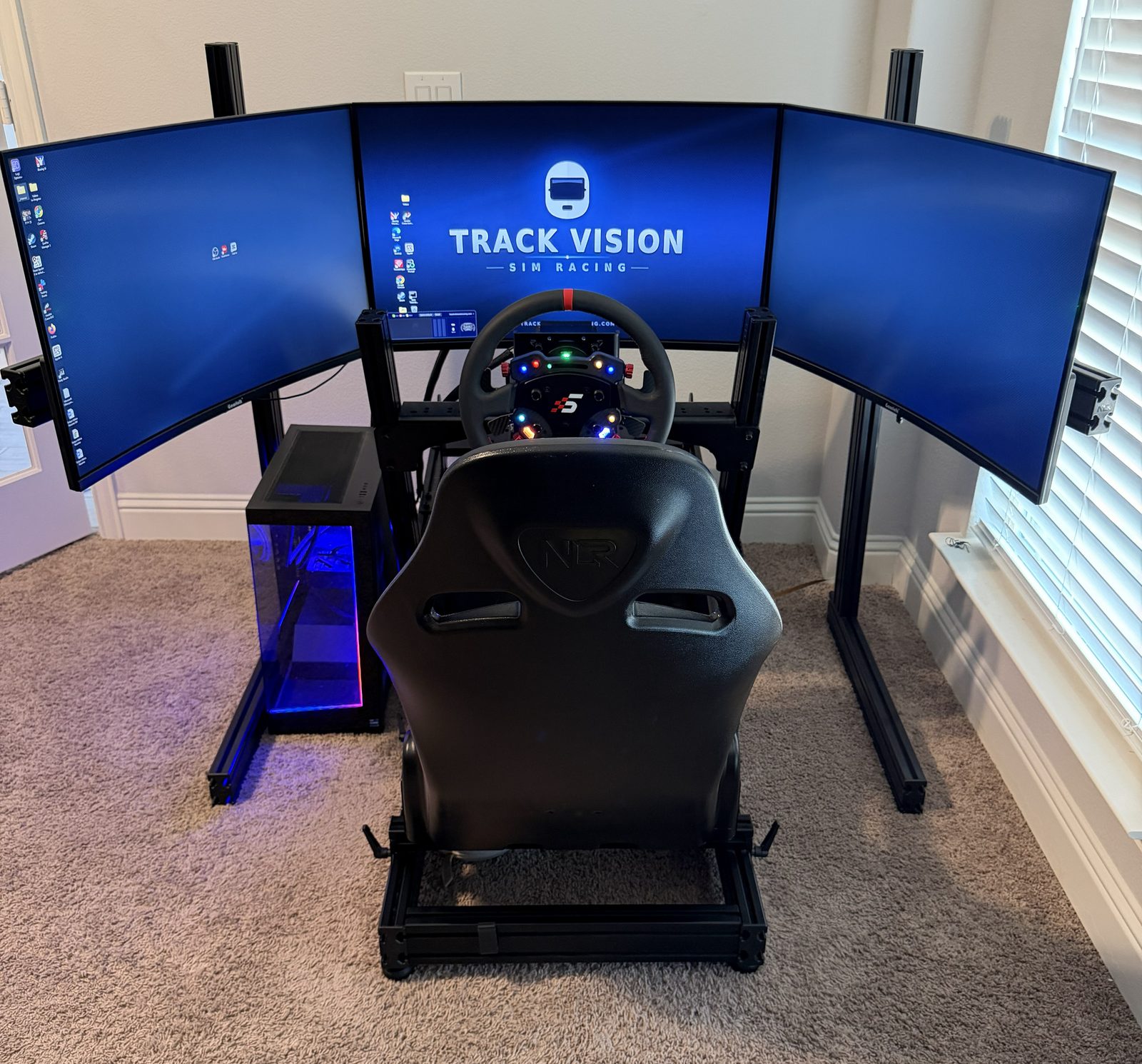 Triple-screen sim rig viewed from behind the seat